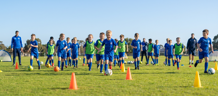 Young players dribbling around cones at a Bonnet Bay FC Bombers Academy soccer clinic on a sunny field